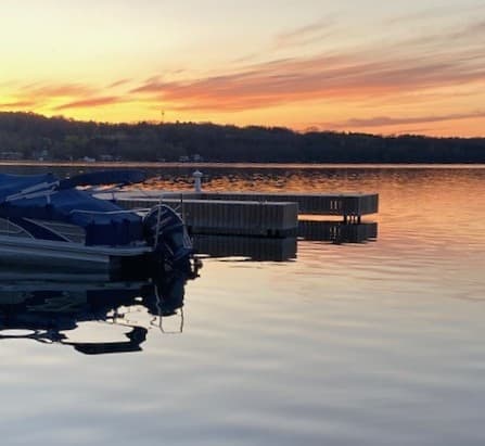 A serene sunset over a lake with boats docked nearby.